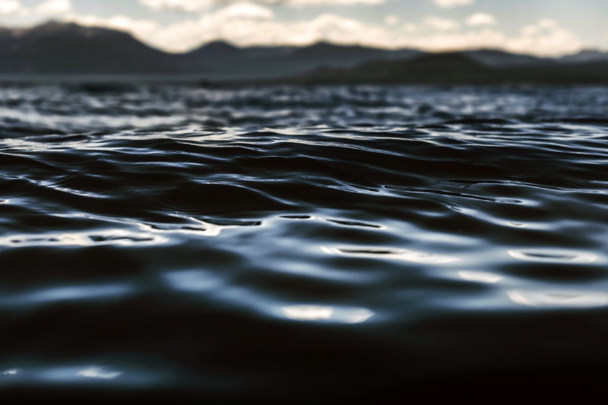 Still lake water under an overcast sky